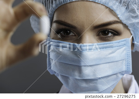 Close up of pretty doctor looking at pill Close up of pretty doctor looking at pill 27296275