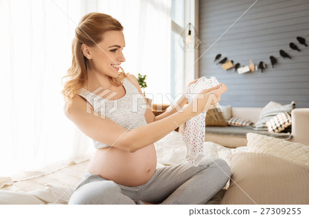 Pregnant woman holding baby clothes Pregnant woman holding baby clothes 27309255