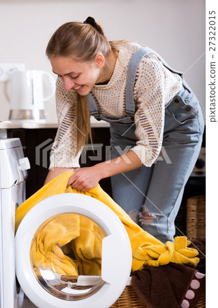 Young woman taking clothes out washing machine Young woman taking clothes out washing machine 27322015