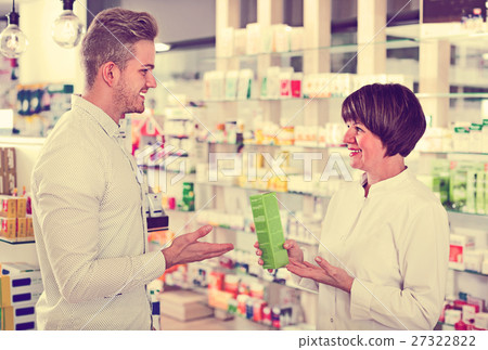 Woman pharmacist helping customers in drug store Woman pharmacist helping customers in drug store 27322822