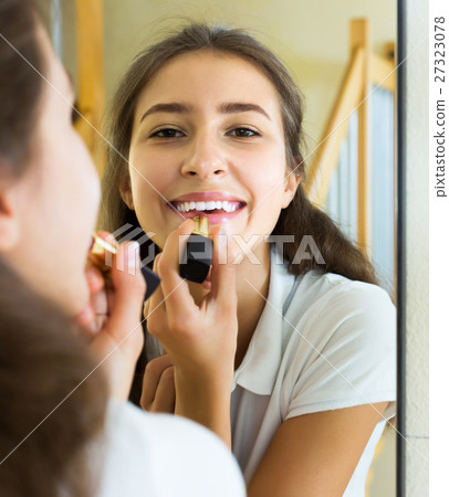 Teenager applying lipstick Teenager applying lipstick 27323078