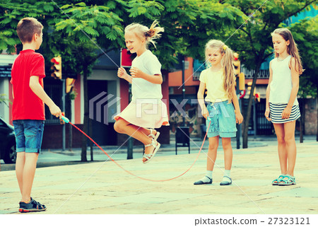 Kids in school age playing together with jumping rope Kids in school age playing together with jumping rope 27323121
