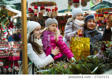 Smiling cheerful family of four buying Caga Tio. Focus on woman 27323131