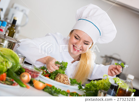 Female chef decorating cheese with herbs and lettuce 27323285