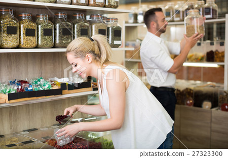 Woman picking dried fruits in store . 27323300