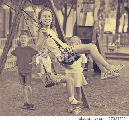 View on children swinging together on children's playground View on children swinging together on children's playground 27323531