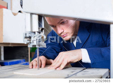 guy using ribbon saw to cut plank at workshop 27323603