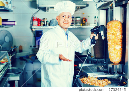 Cheerful mature man cook cutting kebab meat on kitchen Cheerful mature man cook cutting kebab meat on kitchen 27324345