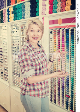 Female next to shelf with threads for sewing 27324506