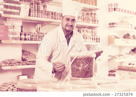 Shop staff standing near containers with olives in flavoured brine Shop staff standing near containers with olives in flavoured brine 27325874