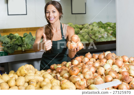 Woman seller wearing apron picking yellow onion bulbs Woman seller wearing apron picking yellow onion bulbs 27325970