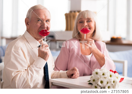 Adorable elderly couple holding up red lollipops 27357805