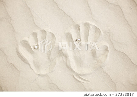 wedding rings with hand print on the sand 27358817