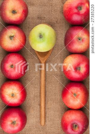 Spoon with green apple lying on the red apples Spoon with green apple lying on the red apples 27385220