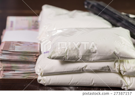 Bags of drugs, pistol and money on table Bags of drugs, pistol and money on table 27387157