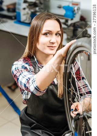 Charming woman repairing the wheel bicycle in the Charming woman repairing the wheel bicycle in the 27396118