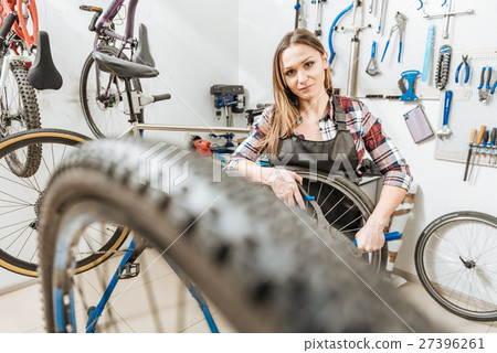 Cheerful young craftswoman working in the garage Cheerful young craftswoman working in the garage 27396261