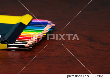 Multicolored pensils in the box on a wooden table. 27396488