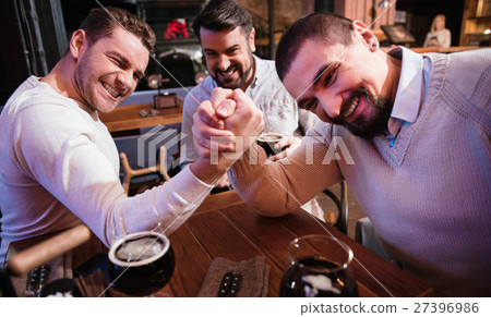 Cheerful pleasant men armwrestling in the pub 27396986