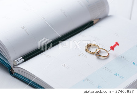 Wedding gold rings on calender with pencil. 27403957