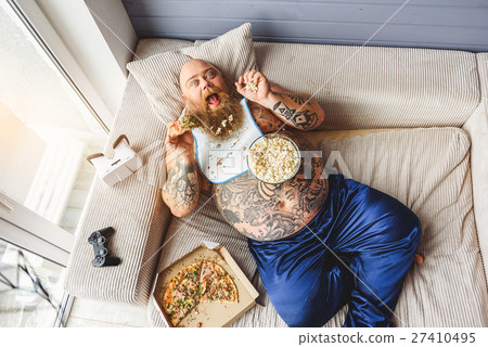 Fat guy eating junk food with enjoyment 27410495