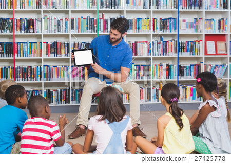 Teacher teaching kids on digital tablet in library 27425778