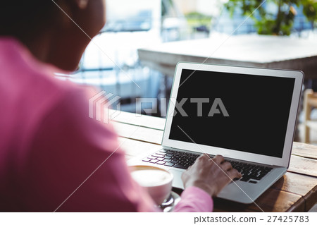 Woman using laptop in cafeteria Woman using laptop in cafeteria 27425783