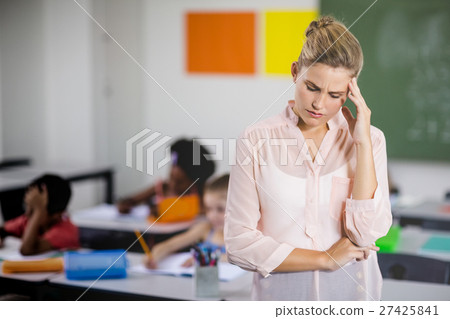 Tensed school teacher standing in classroom 27425841