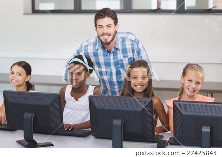 Teacher assisting schoolgirls in learning computer 27425843