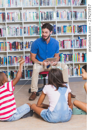 Teacher teaching kids on digital tablet in library Teacher teaching kids on digital tablet in library 27425957