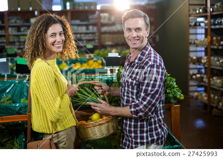 Happy couple buying vegetables in organic section Happy couple buying vegetables in organic section 27425993
