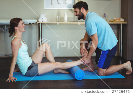 Physiotherapist doing leg therapy to a woman using foam roll Physiotherapist doing leg therapy to a woman using foam roll 27426475