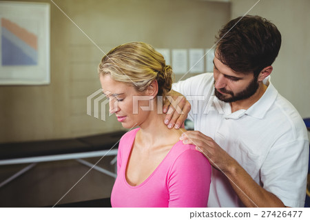 Male physiotherapist giving neck massage to female patient 27426477