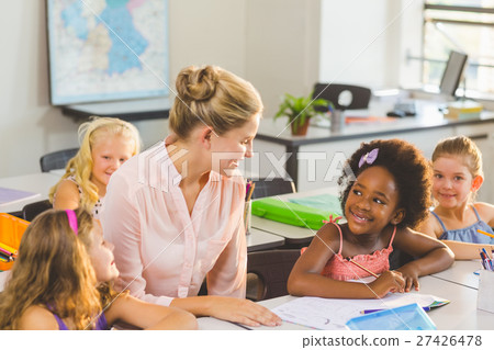 Teacher helping kids with their homework in classroom 27426478