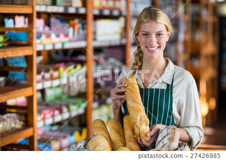 Smiling female staff holding loaf of bread at bread counter 27426985