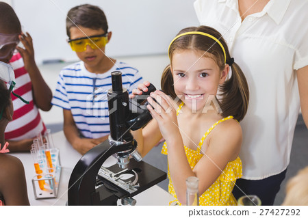 Schoolgirl holding microscope in laboratory 27427292