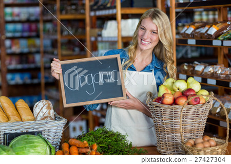 Smiling staff holding organic sign board in organic section 27427304