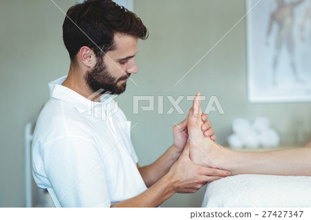 Physiotherapist giving foot massage to a woman 27427347