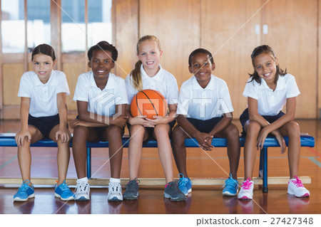 Portrait of school kids sitting in basketball court 27427348