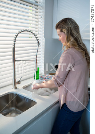 Woman washing bowl under sink in kitchen Woman washing bowl under sink in kitchen 27427872