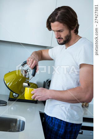 Man pouring coffee into cup in kitchen Man pouring coffee into cup in kitchen 27427881