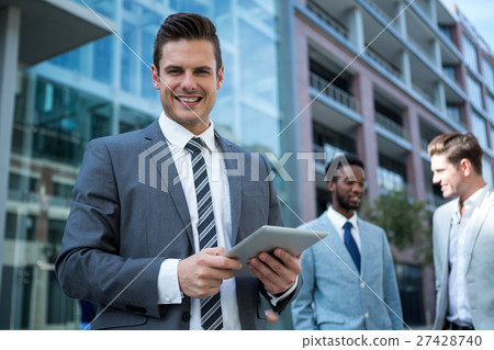 Smiling businessman using digital tablet in the office building Smiling businessman using digital tablet in the office building 27428740