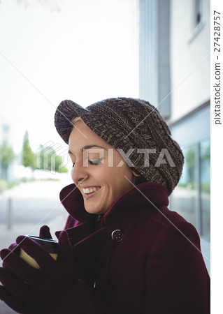 Woman smiling and holding a cup of coffee Woman smiling and holding a cup of coffee 27428757