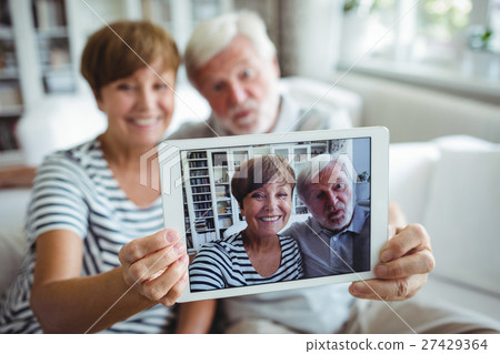 Senior couple clicking a picture on digital tablet 27429364