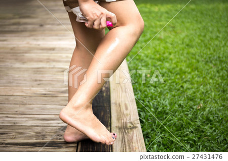 Woman spraying insect repellent on her leg 27431476