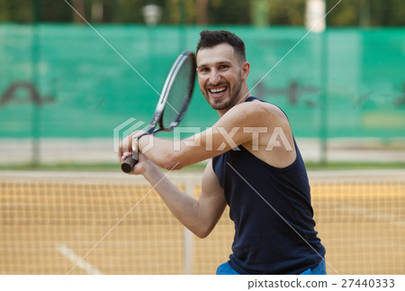 Happy young man playing on tennis clay court. 27440333