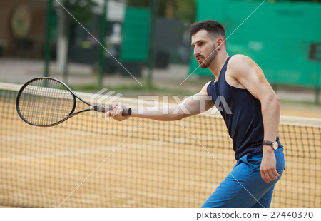 Happy young man playing on tennis clay court. 27440370