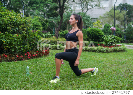 Slim athletic woman working out in park doing knee 27441797