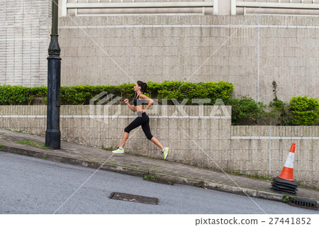 Female runner running uphill on town street Female runner running uphill on town street 27441852