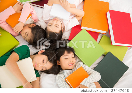 Young Students Lying On Their Backs With Piles Of Books 27447648